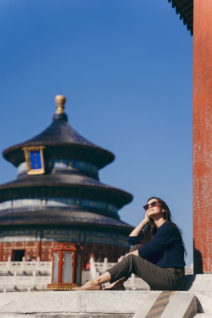 Mujer apreciando la vista de Beijing con un templo detrás